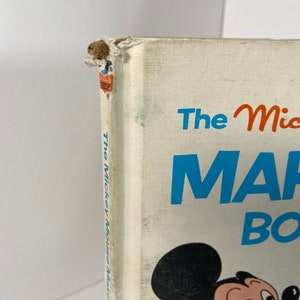 May include: The cover of a vintage children's book featuring Mickey Mouse. The book is titled "The Mickey Mouse Make-Believe Book".