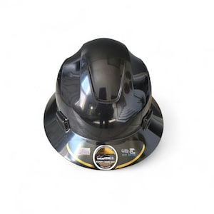 May include: A black safety hard hat with a wide brim. The hard hat has a glossy finish and a sticker with the text "TRUE CREST SAFETY HARD HAT". The sticker also includes the text "COOL AIR FLOW FAST SYSTEM".