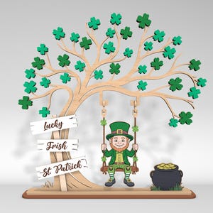 May include: A wooden St. Patrick's Day decoration featuring a tree with green shamrock leaves. A leprechaun swings from the tree, and a pot of gold sits nearby. The sign reads "Lucky", "Irish", and "St. Patrick".