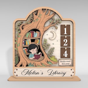 May include: Wooden bookshelf-themed decor with a girl reading a book inside a tree. The design includes a bookshelf, a moon, stars, and a counter for books read. The text reads "Melisa's Library" and "Books read this year."