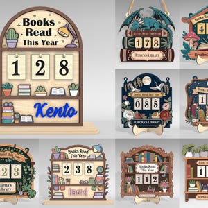 May include: Wooden book counter displays with the text "Books Read This Year." Each counter features a number display, with some showing a name. Designs include a dragon, mushrooms, flowers, and a cat. The counters are on a wooden base.
