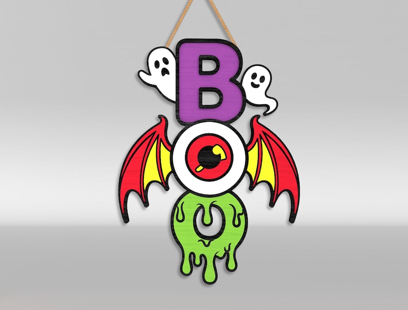 Op de afbeelding: Een hangend houten wandbord met de tekst BOO, bestaande uit een paarse letter B, een centraal oog met rode en gele vleermuisvleugels, en een druipende limoengroene letter O. Twee kleine witte spookjes bevinden zich aan weerszijden van de letter B.