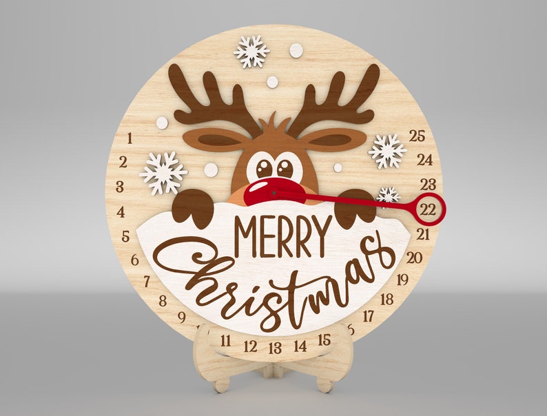 K&ouml;nnte beinhalten: Ein h&ouml;lzerner Weihnachts-Countdown-Kalender mit einem Rentier-Design. Die Uhr hat eine rote Nase und einen roten Zeiger, der sich um die Zahlen von 1 bis 25 bewegt. Die Uhr zeigt auf der Vorderseite "Frohe Weihnachten" an.