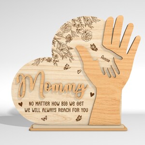 May include: Wooden heart-shaped sign with the word "Mommy" and the text "No matter how big we get we will always reach for you". The sign features two hands reaching up, with the name "Anna" inscribed on one hand.