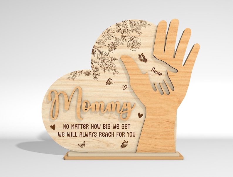 May include: Wooden heart-shaped sign with the word "Mommy" and the text "No matter how big we get we will always reach for you". The sign features two hands reaching up, with the name "Anna" inscribed on one hand.