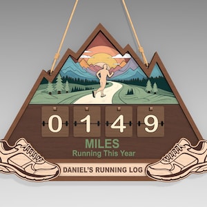 Peut inclure: Panneau en bois en forme de montagne pour le suivi de la course à pied. Il présente un coureur sur un chemin, un coucher de soleil et un compteur affichant "0149" miles. Comprend deux découpes de chaussures et le texte "MILES Running This Year" et "DANIEL'S RUNNING LOG".