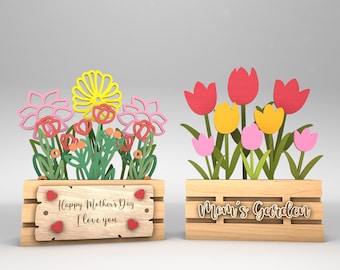 Peut inclure: Deux boîtes à fleurs en bois avec des fleurs en papier colorées. La boîte de gauche dit "Joyeuse fête des mères Je t'aime" et la boîte de droite dit "Le jardin de maman".