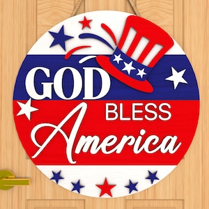 Puede incluir: Un letrero redondo de madera con un esquema de color rojo, blanco y azul. El letrero dice "God Bless America" con un sombrero de dibujos animados de Tío Sam y fuegos artificiales en el fondo.