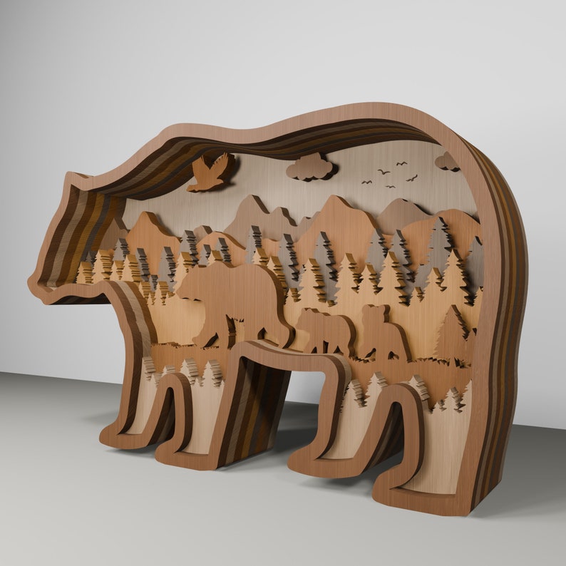 K&ouml;nnte beinhalten: Eine Holz-B&auml;rensilhouette mit einem geschichteten Design. Das Innere des B&auml;ren ist ausgeschnitten, um eine Waldszene mit Bergen, B&auml;umen und B&auml;ren zu zeigen.