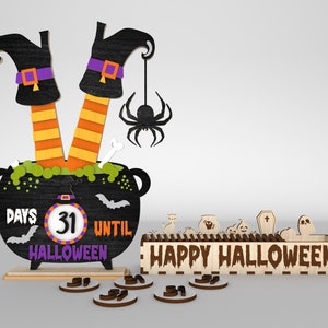 May include: Wooden Halloween countdown calendar with a witch's legs sticking out of a cauldron. The cauldron has a chalkboard with the text "Days 31 Until Halloween". There are also wooden numbers and a separate wooden sign that says "Happy Halloween".