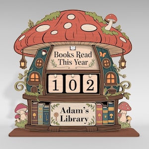 May include: A whimsical wooden book counter shaped like a mushroom house. The counter displays "Books Read This Year" and the number "102". The base reads "Adam's Library". The design features a red mushroom cap, green accents, and small details.