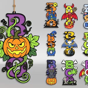 Op de afbeelding: Een collectie hangende houten decoraties met het woord BOO in diverse kleurrijke ontwerpen. Elk stuk toont illustraties in Halloween-thema, waaronder pompoenen, geesten, katten, vleermuizen, skeletten en spookhuizen met levendige verf.