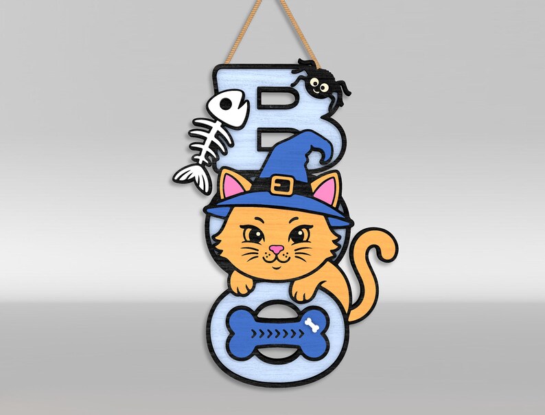 Op de afbeelding: Een hangend wandbord met de tekst BOO in lichtblauwe letters. De letter B is voorzien van een wit vissenskelet en een zwarte spin. Een oranje kat met een blauwe heksenhoed zit in het midden en de letter O bevat een blauwe botvorm.