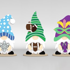 May include: Three wooden gnome figurines. One gnome wears a blue and white winter hat and holds a snowflake. Another gnome has a green and white striped hat and a football. The third gnome has a purple hat and a mask, holding a purple crawfish.