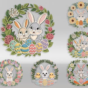 May include: A collection of Easter-themed wooden wreaths. Each wreath features a bunny or bunnies, Easter eggs, and floral elements. The wreaths are in various designs, with a color palette of pastels and natural wood tones.