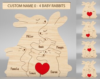 May include: A wooden cutout of a family of rabbits with a red heart in the center. The names Miller, Anais, Maggie, Pamela, Tomos, and Ciaran are written on the cutout.