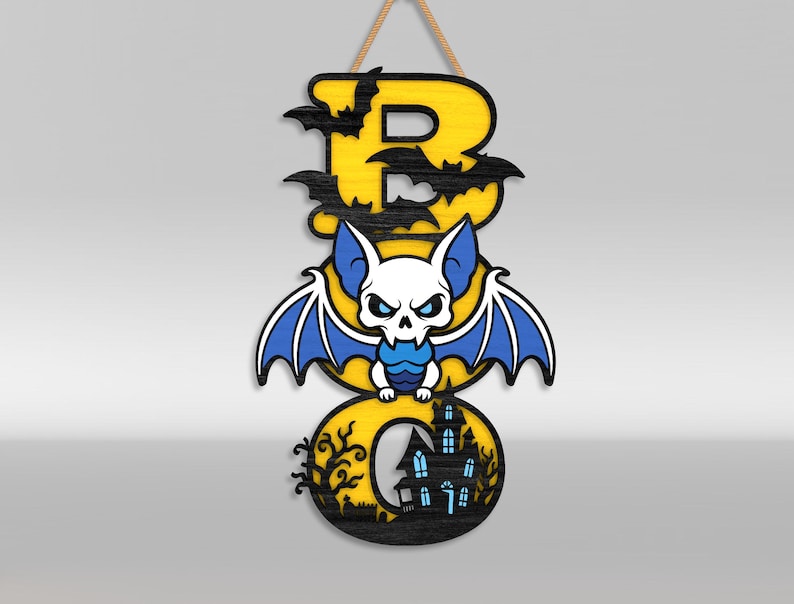 Op de afbeelding: Een verticaal hangend bord met het woord BOO in gele letters met zwarte omlijning. De letter B is versierd met zwarte vleermuissilhouetten. Een wit en blauw vleermuisfiguur zit tussen de letters. De letter O bevat een afbeelding van een zwart spookhuis.