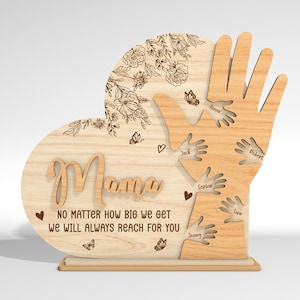 May include: Wooden heart-shaped sign with the word "Mama" and the text "No matter how big we get we will always reach for you". The sign features a cutout design of hands reaching up towards the word "Mama" with names written on each hand.