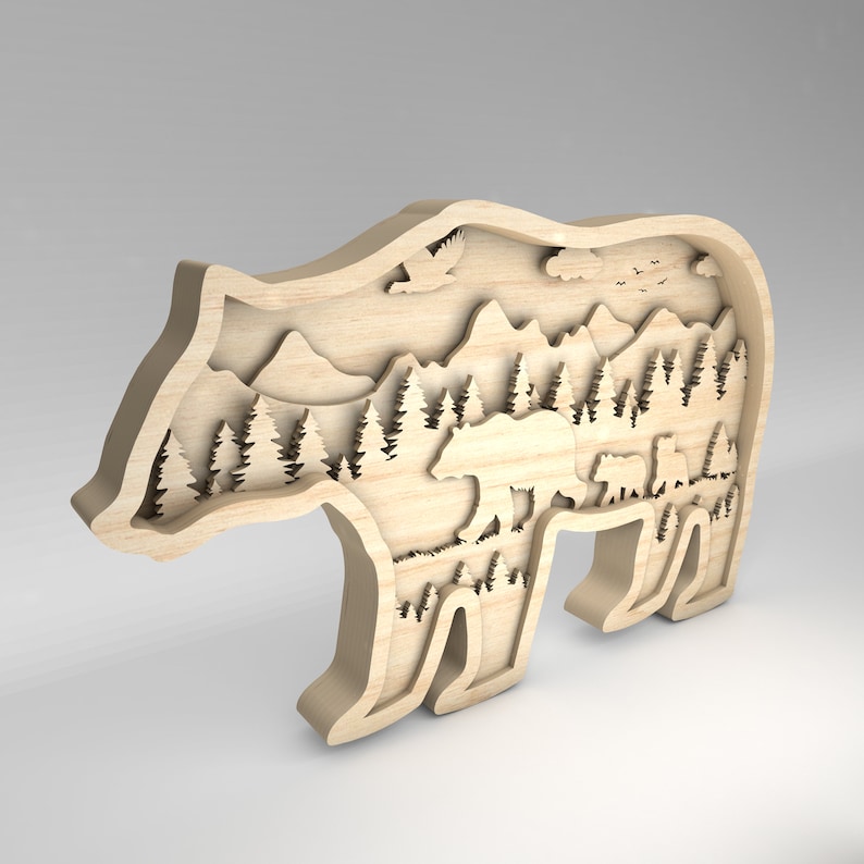 K&ouml;nnte beinhalten: Eine Holz-B&auml;rensilhouette mit einem detaillierten Ausschnitt-Design einer Waldszene, einschlie&szlig;lich Bergen, B&auml;umen und einer B&auml;renfamilie. Der B&auml;r steht auf einem hellbraunen Hintergrund.