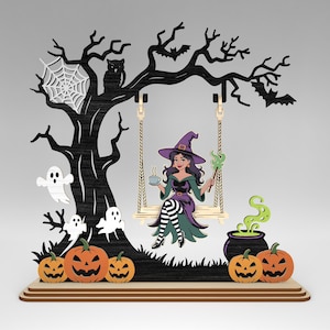 May include: A Halloween-themed wooden decoration featuring a witch on a swing under a spooky tree. The scene includes pumpkins, ghosts, an owl, and a cauldron with green smoke. The witch is wearing a purple hat and holding a wand.