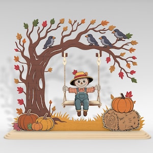 Könnte beinhalten: Herbstliche Holzdekoration mit einer Vogelscheuche auf einer Schaukel unter einem Baum mit bunten Blättern und Vögeln. Kürbisse und ein Heuballen vervollständigen die Herbstszene. Der Sockel ist hellbraun.