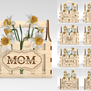 May include: Wooden flower box with a fence design, holding white and yellow daffodils. The box has a decorative sign that says "I love you, Mom". Other boxes with similar designs are also shown.