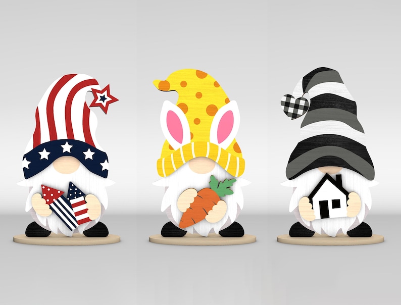 May include: Three wooden gnome figurines. One wears a red, white, and blue hat with a star and holds fireworks. Another has a yellow hat with bunny ears and holds a carrot. The third gnome has a black and white hat and holds a house.