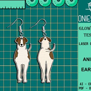 May include: A pair of laser cut wooden earrings featuring a brown and white dog. The earrings are designed to look like the dog is standing on its hind legs. The earrings are labeled "Animal Earring" and "Glowforge Tester".