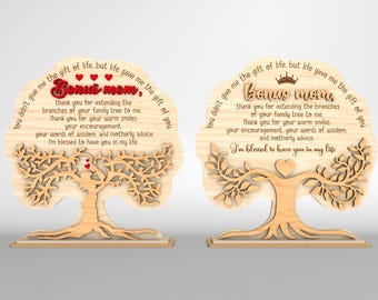 May include: Two wooden tree-shaped plaques with the text "Bonus Mom" and a heartfelt message. The plaques feature a tree design with intricate cutouts, hearts, and a crown. The text is in a script font, and the overall design is a light brown color.