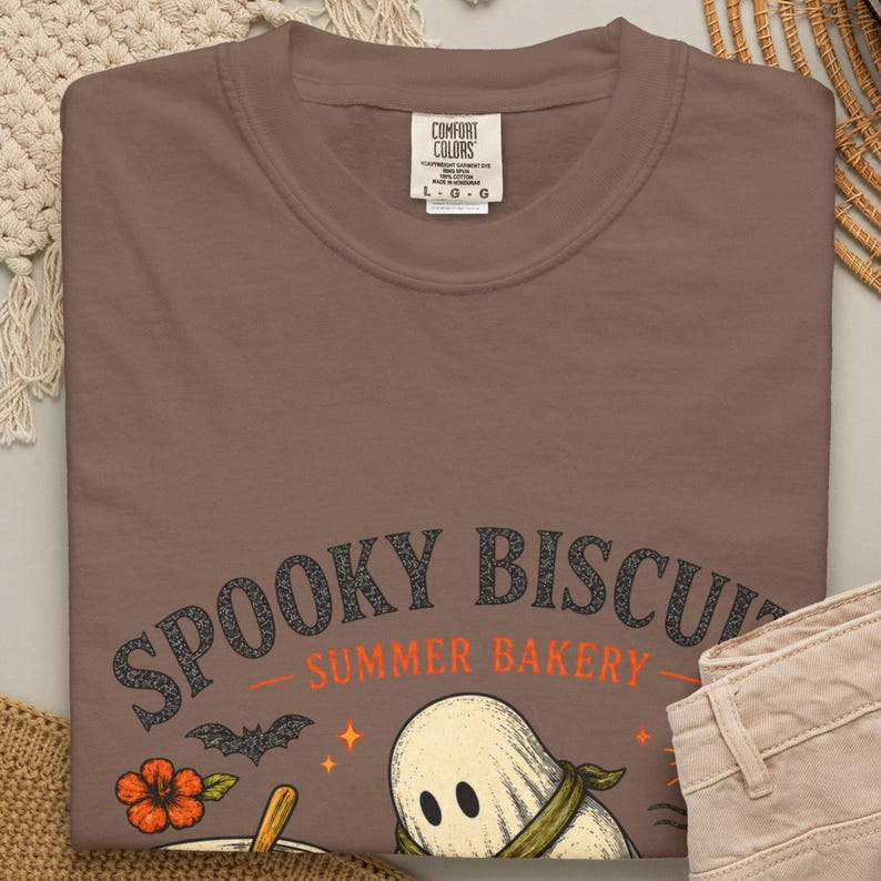 Summerween bakery shirt featuring a friendly ghost making dough with the funny phrase “Spooky Biscuits.” This garment-dyed Comfort Colors Halloween tee offers a vintage-inspired look and relaxed fit, perfect for bakers, ghost lovers, spooky season parties, vacations, and everyday summer wear.