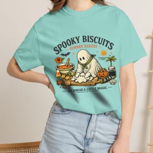 Cute spooky bakery tee featuring an adorable ghost making biscuits and the playful wording “Spooky Biscuits.” This Comfort Colors Summerween shirt combines Halloween magic with warm summer vibes, perfect for bakers, ghost fans, beach trips, pool parties, vacations, and spooky season outfits.