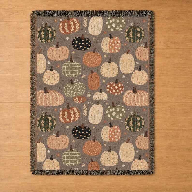 Autumn patchwork throw blanket showcasing pumpkins in mixed decorative patterns with colorful florals and botanical accents. Rich fall colors and tasseled fringe make it a cozy statement piece for farmhouse decor, pumpkin season, and Halloween celebrations.