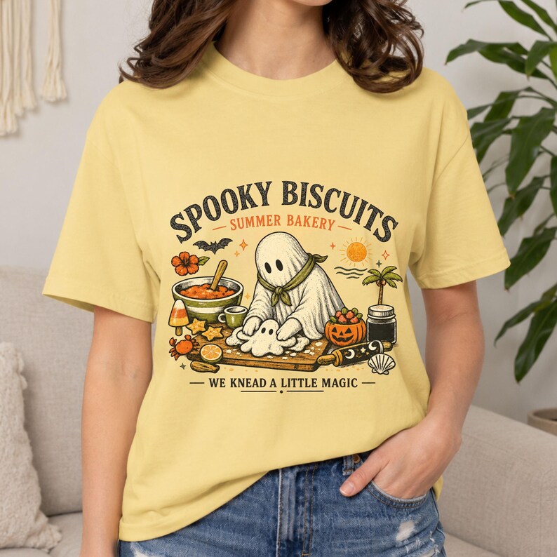 Spooky top for Halloween featuring an adorable ghost kneading biscuit dough in a charming Summerween bakery scene. The playful “Spooky Biscuits” design gives this Comfort Colors shirt a magical seasonal look for bakers, ghost enthusiasts, summer celebrations, and casual spooky outfits.