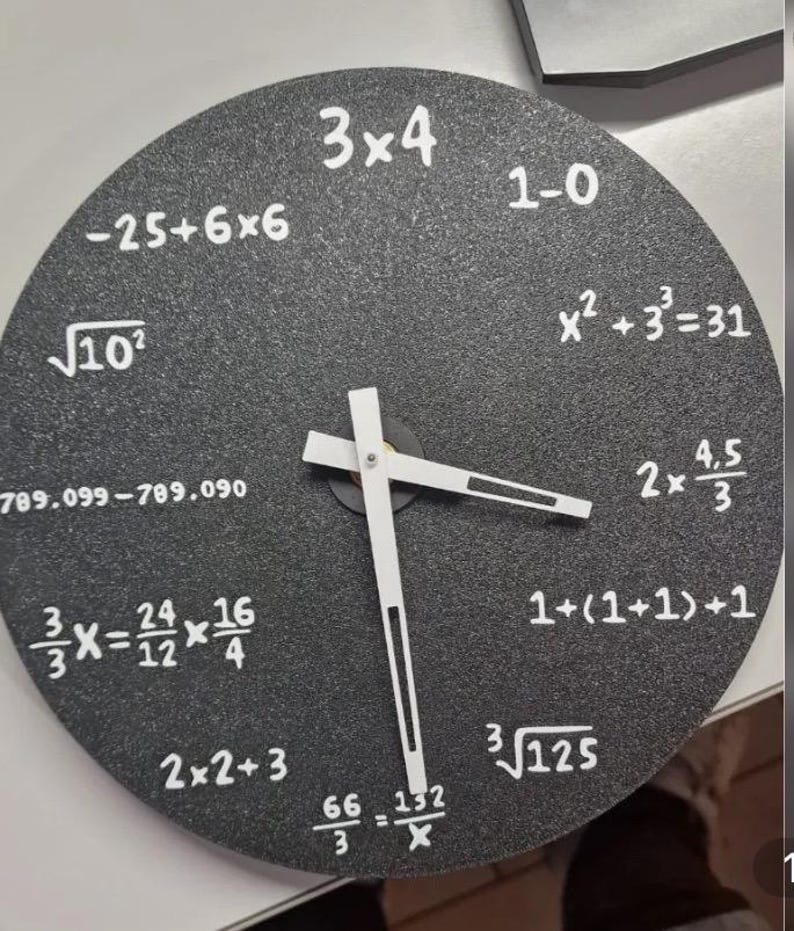 May include: A circular black wall clock featuring white hands and mathematical equations instead of numbers. The hands indicate approximately 3:15. The clock face has a textured finish. The clock's diameter is approximately 25 cm.