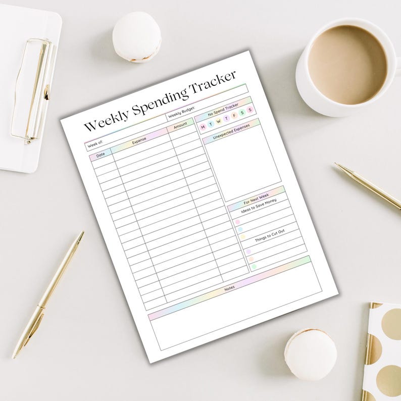 May include: A white Weekly Spending Tracker sheet with pastel-colored accents. The sheet includes sections for expenses, budget, and notes. A cup of coffee, pens, and a clipboard are also on the table.