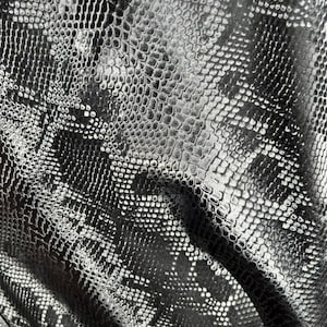 May include: Close-up of a fabric with a snakeskin pattern. The material is a shiny black and silver, with a textured surface that mimics the scales of a snake. The pattern is detailed and realistic.