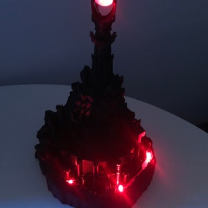 May include: A black 3D printed model of the Dark Tower from The Lord of the Rings, with red LED lights illuminating the tower and the Eye of Sauron at the top.