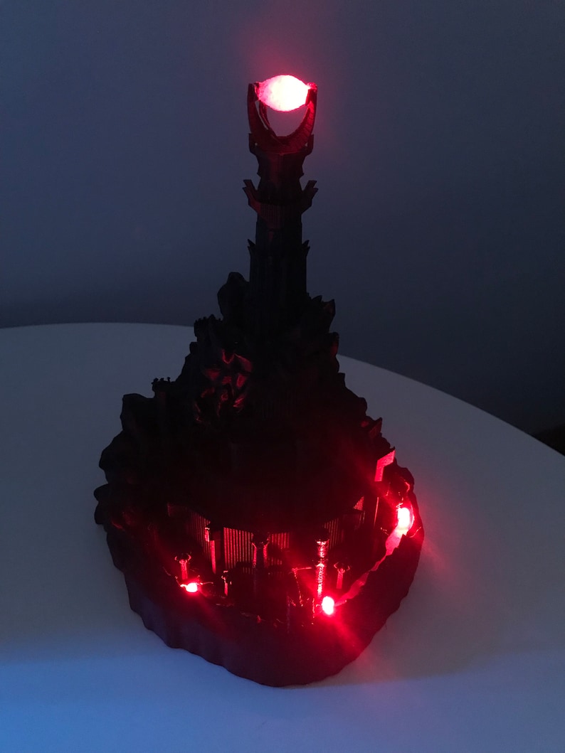 May include: A black 3D printed model of the Dark Tower from The Lord of the Rings, with red LED lights illuminating the tower and the Eye of Sauron at the top.