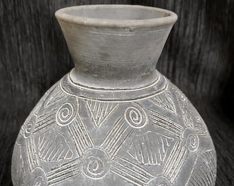 Op de afbeelding: Grijze keramische vaas met een bolvormige body en een uitlopende hals. De vaas heeft een geëtst ontwerp van spiralen en geometrische vormen. De vaas is ongeveer 20 cm hoog en 15 cm breed, met een matte afwerking.