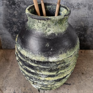 Könnte beinhalten: Eine schwarze und grüne Keramikvase mit einem strukturierten, geschichteten Design. Die Vase hat eine breite Öffnung und einen runden Körper.