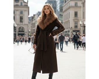 May include: A long, dark brown coat with a fur collar and decorative embroidery on the sleeves. The coat is belted at the waist and worn with black boots. The background shows a city street with pedestrians.