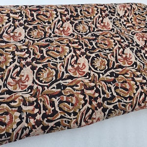 May include: A black fabric with a beige and brown floral pattern. The fabric is quilted with white thread.