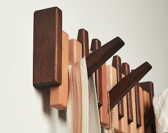 May include: A set of wooden wall hooks in various shades of brown and beige. The hooks are arranged in a staggered pattern and have a modern, minimalist design.
