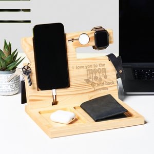 May include: Wooden phone stand with a charging cable, watch holder, key hook, and a small compartment for a wallet or other items. The stand is engraved with the message "I love you to the moon and back".