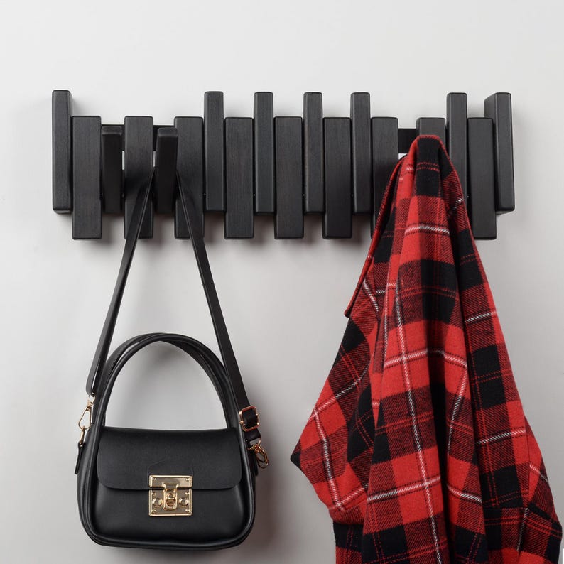 Peut inclure: Un porte-manteau mural en bois noir avec une chemise &agrave; carreaux rouge et noir et un sac &agrave; main noir accroch&eacute;s.