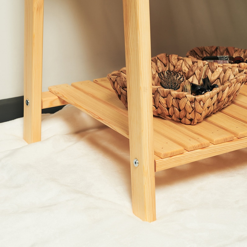 May include: A wooden shelf unit with two shelves and a woven basket on the bottom shelf.