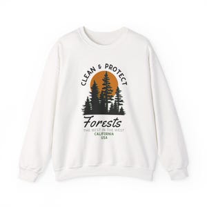 May include: White sweatshirt with a graphic design featuring a sunset, trees, and the words "Clean & Protect Forests." Below the graphic, the text reads "The Best in the West, California, USA."