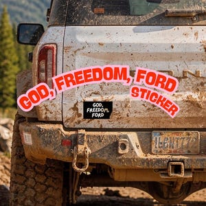 Op de afbeelding: Een rechthoekige zwarte sticker met witte tekst "GOD, FREEDOM, FORD" aangebracht op de met modder bespatte witte achterklep van een terreinwagen. De sticker heeft een eenvoudig, vet lettertype en is centraal op het achterpaneel geplaatst.