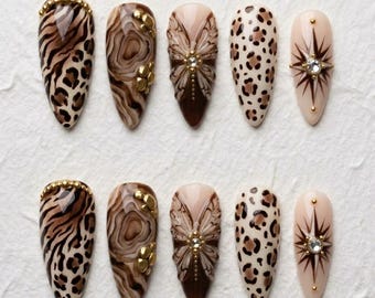 Uñas postizas con estampado animal marrón, uñas con estampado de leopardo y cebra, set de uñas con mariposa 3D, uñas de lujo hechas a mano, uñas almendradas nude, uñas postizas glamurosas.