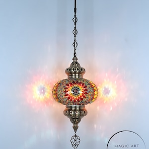 May include: A colorful mosaic Turkish lamp with a brass chain and ornate details. The lamp is lit and casting a warm glow. The text "MAGIC ART TURKISH LAMP Mosaic Lights" is visible below the lamp.